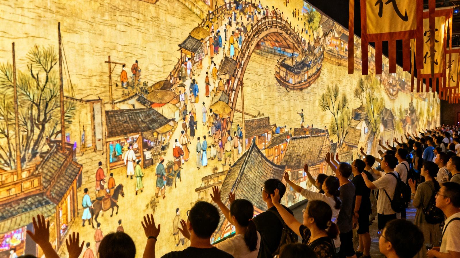 杭州宋城景区内一面28米长的古风墙面上，AR投影展示着动态清明上河图场景，众多游客聚集在墙前用手势与画面互动，周围悬挂宋代风格旗帜
